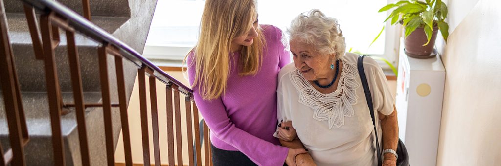 Caregiver helping senior woman climb staircase